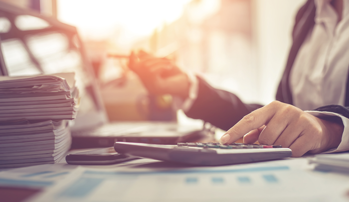 business person sitting at desk with calculator