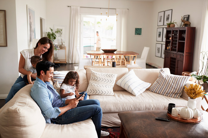 happy family on couch browsing health insurance options on tablet