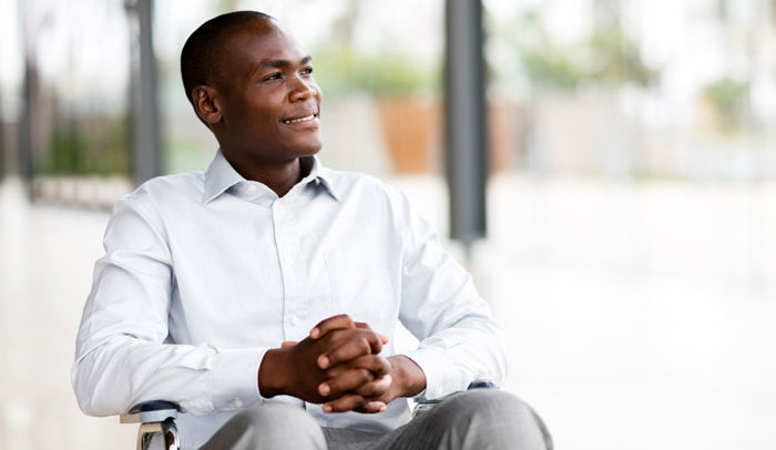 young African American lawyer with disabilities in wheelchair smiling thoughtfully out the window